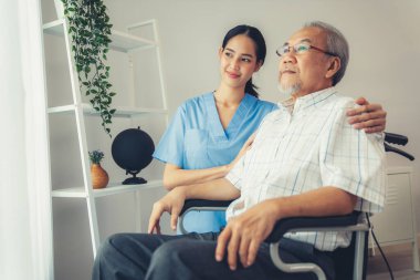 Caring nurse and a contented senior man in a wheel chair at home, nursing house. Medical for elderly patient, home care for pensioners.