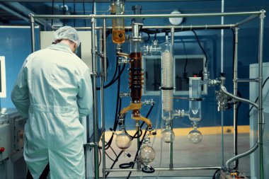 Bilim adamı ya da eczacı tıbbi ve sağlık hizmetleri için kenevir yağı çıkarıyor. Esrar ürünlerinden alınan sağlık hizmetleri eczanesi. Cam tüpler ve teçhizatlı kenevir yağı çıkarma makinesi.