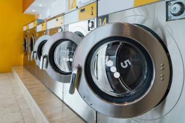 Halka açık bir mağazada kaliteli para ile çalışan bir dizi çamaşır makinesi. Kamu dairesinde ticari çamaşır ve kurutma makinesi kavramı.