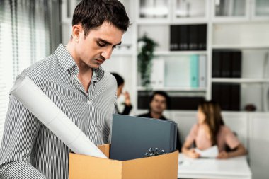 Depressed and disappointed employee packing his belongings after being fired for not being competent. Gossiped by his colleagues behind his back. Layoff due to economic depression.