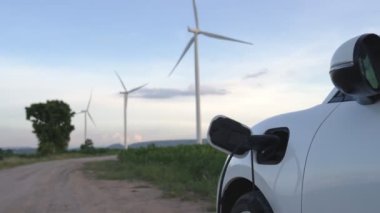 Çevreyi korumak için rüzgar türbininden yeşil ve yenilenebilir enerjiyle çalışan şarj istasyonunda şarj edilen gelişmiş gelecek enerji altyapısı konsepti.