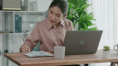 Ofiste çalışan ve dizüstü bilgisayar yazan hevesli bir iş kadını. Masasında oturmuş laptopla çalışan güzel bir ofis hanımı..