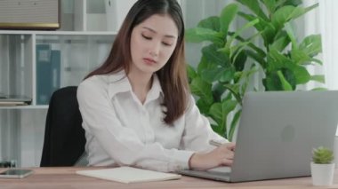 Ofiste çalışan ve dizüstü bilgisayar yazan hevesli bir iş kadını. Masasında oturmuş laptopla çalışan güzel bir ofis hanımı..