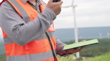 Kırsal kesimdeki bir tepenin tepesinde ya da dağda rüzgar çiftliğinde çalışan bir mühendis. Yenilenebilir ve sürdürülebilir enerjinin gelecekteki üretimi için yenilikçi bir ideal. Rüzgar türbininden enerji üretimi.