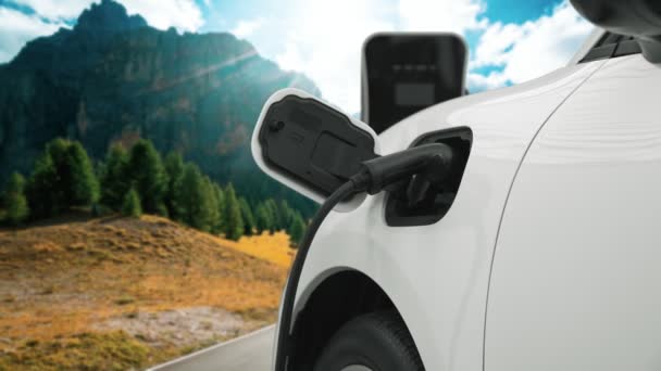 電気発生器ドライブによるエネルギー持続可能な車の電源 プログレッシブ旅行の概念のための山の背景と充電ステーションでバッテリーを充電します クリーン環境のシンボルとして自然界のEv車 — ストック動画