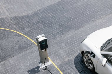 Aerial top view image of progressive green energy-powered charging station, electric vehicle at public car park with EV car concept for alternative transportation and energy infrastructure.