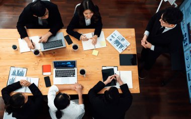 Top view manager or office worker give presentation in harmony conference room to business colleague, BI data dashboard on screen and pile of financial analyzed data reports on meeting table.