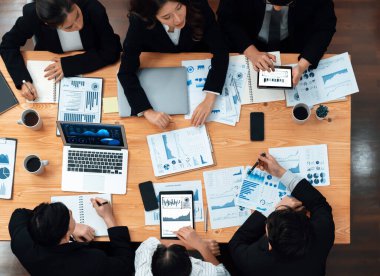 Top-view business team of financial data analysis meeting with business intelligence, report paper and dashboard on laptop for marketing strategy. Business people working together in office of harmony