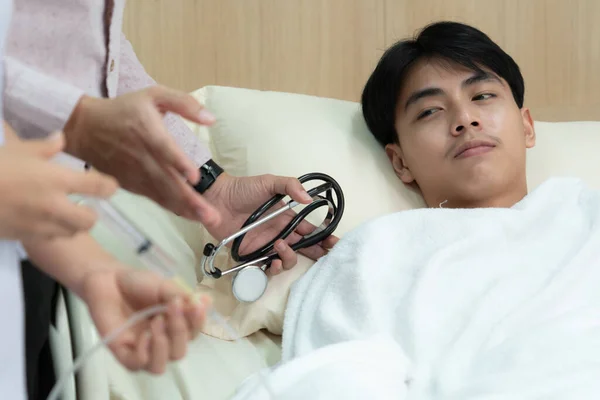 stock image Doctor and nurse inject medicine, dosage into IV tube providing medical treatment to patient in sterile room at hospital. Fragile patient receive medical care on sick bed in recovery room.