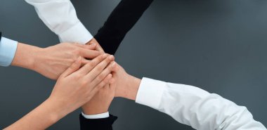 Top view partial hands wearing formal suit joining stack and form circle as symbol of team building, unity and harmony in office workplace. Successful business team of synergy holding hand together.