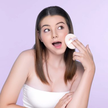 Facial cosmetic makeup concept. Portrait of young charming girl applying dry powder foundation. Beautiful girl smiling with perfect skin putting cosmetic makeup on her face.