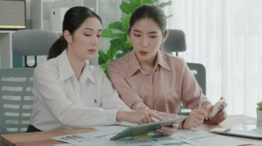 Ofis çalışma alanında birlikte çalışan iki genç hevesli iş kadını. Genç meslektaşlar tartışırken ve dizüstü bilgisayar kullanırken. Modern ofis çalışanları masada birlikte oturuyorlar..