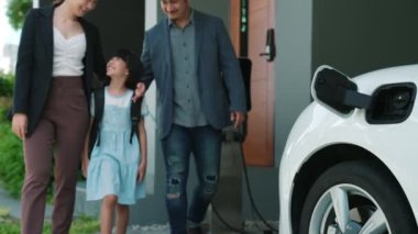 Elektrikli arabası ve şarj istasyonu olan yenilikçi bir genç aile ve kız. Sağlıklı çevre için elektrikli araçlardan gelen yeşil ve temiz enerji. Yenilenebilir kaynaktan eko güç.