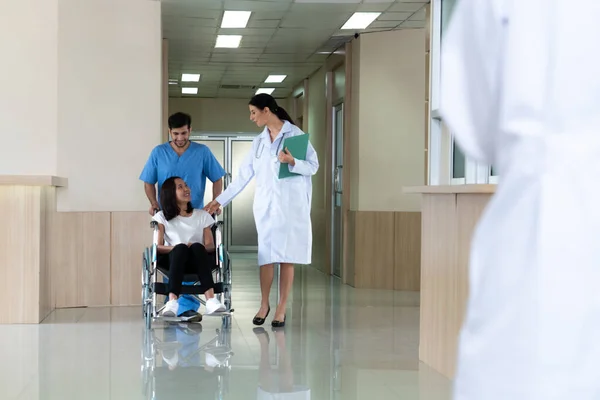 의사와 간호사는 복도를 휠체어를 환자를 신체장애자를 관리와 — 스톡 사진