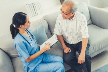 A young female doctor inquires about personal information of a contented senior at home. Medical care for the elderly, elderly illness, and nursing homes, home care.