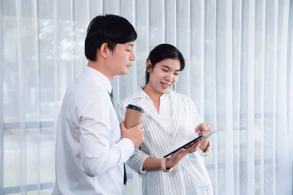 stock image Manager advising guiding younger colleague with tablet in workplace. Couple businesspeople in formal wear working together on financial strategy as concept of teamwork and harmony in office.