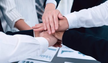 Top view closeup business team of suit-clad businesspeople join hand stack together. Colleague collaborate and work together to promote harmony and teamwork concept in office workplace.