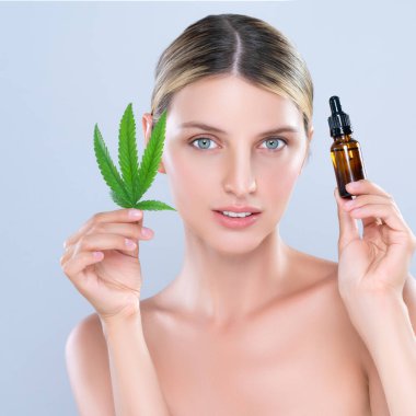 Alluring portrait of beautiful woman in isolated holding green leaf with marijuan extracted bottle for skincare treatment product. Cannabis CBD oil for cosmetology and beauty concept.