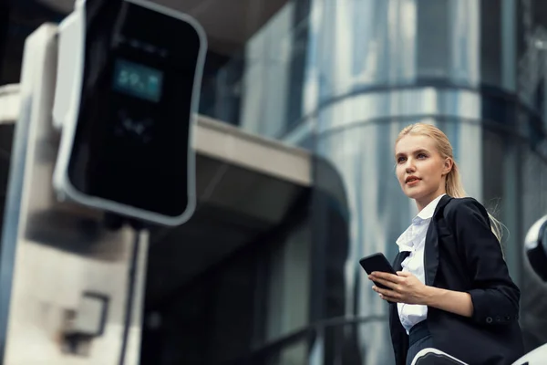Businesswoman Wearing Black Suit Using Smartphone Leaning Electric Car Recharge — Φωτογραφία Αρχείου