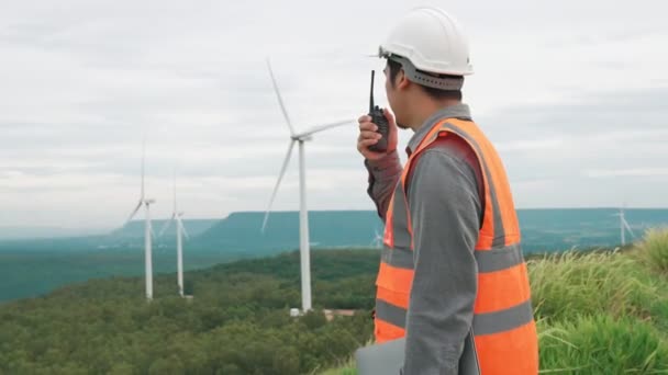 田舎の丘や山の上の風力発電所で働くエンジニア 再生可能エネルギー 持続可能なエネルギーの将来の生産のための進歩的な理想 風力タービンからの発電 — ストック動画
