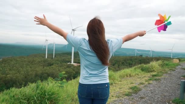 風力タービン農場で彼女の時間を楽しんで進歩的な幸せな女性の概念 水平線に丘や山を持つ国側の風力発電機による風力発電機 — ストック動画