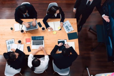 Top view manager or office worker give presentation in harmony conference room to business colleague, BI data dashboard on screen and pile of financial analyzed data reports on meeting table.