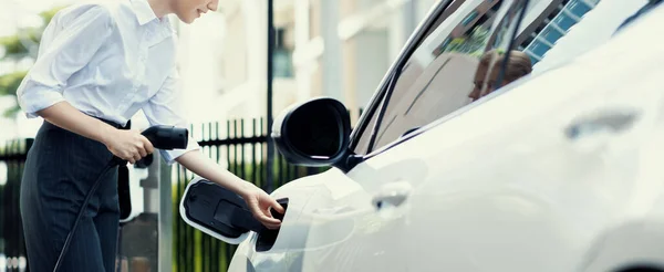 Closeup Progressive Businesswoman Smartphone Leaning Electric Car Charging Station Driving — стоковое фото