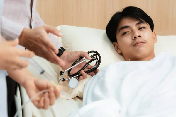 stock image Doctor and nurse inject medicine, dosage into IV tube providing medical treatment to patient in sterile room at hospital. Fragile patient receive medical care on sick bed in recovery room.