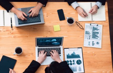 Top-view closeup business team of financial data analysis meeting with business intelligence, report paper and dashboard on laptop. Business group people working together in harmony office.