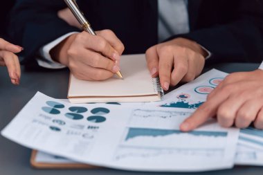 Closeup on BI dashboard on meeting desk with businesspeople analyzing or planning business strategy with hands pointing on financial paper reports as concept of harmony in office workplace.