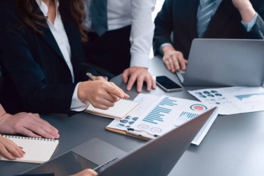 Closeup on BI dashboard on meeting desk with businesspeople analyzing or planning business strategy with hands pointing on financial paper reports as concept of harmony in office workplace.