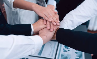 Top view closeup business team of suit-clad businesspeople join hand stack together. Colleague collaborate and work together to promote harmony and teamwork concept in office workplace.