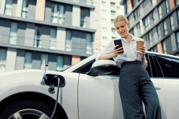 Focus Businessman Using Phone Leaning Electric Vehicle Holding Coffee Blurred — Stockfoto