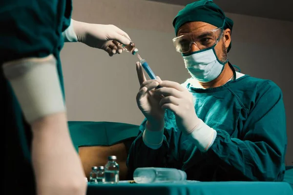 外科医生在无菌手术室用药瓶充填注射器进行外科手术 并配备辅助护士 全副武装的医生和医护人员准备麻醉注射 — 图库照片