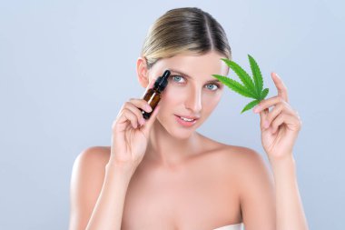 Alluring portrait of beautiful woman in isolated holding green leaf with marijuan extracted bottle for skincare treatment product. Cannabis CBD oil for cosmetology and beauty concept.