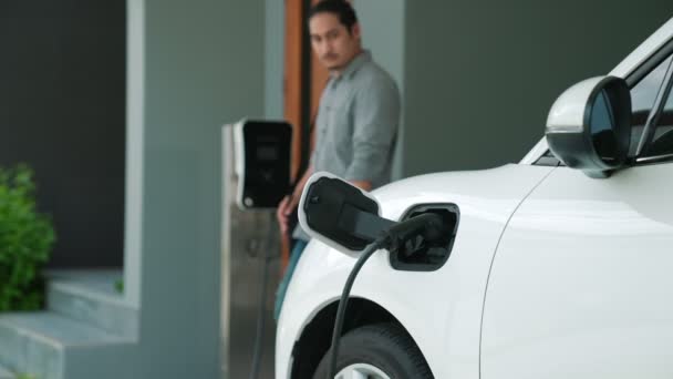 Mężczyzna Odłącza Ładowarkę Elektryczną Swoim Mieszkaniu Koncepcja Stosowania Pojazdów Elektrycznych — Wideo stockowe