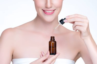 Closeup personable portrait of beautiful woman applying essential oil bottle for skincare product. Cannabis extracted CBD oil dropper for treatment and cannabinoids concept in isolated background.