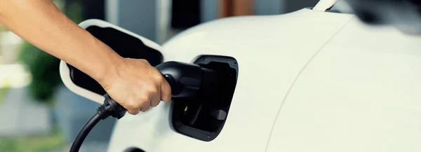 stock image Progressive concept of hand insert an emission-free power connector to the battery of electric vehicle at home. Electric vehicle charging via cable from charging station to EV car battery