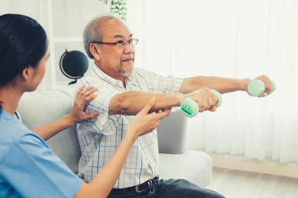 stock image Contented senior patient doing physical therapy with the help of his caregiver. Senior physical therapy, physiotherapy treatment, nursing home for the elderly