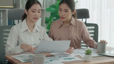 Ofis çalışma alanında birlikte çalışan iki genç hevesli iş kadını. Genç meslektaşlar tartışırken ve dizüstü bilgisayar kullanırken. Modern ofis çalışanları masada birlikte oturuyorlar..