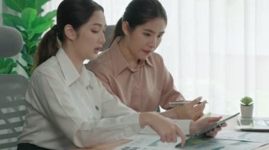 Ofis çalışma alanında birlikte çalışan iki genç hevesli iş kadını. Genç meslektaşlar tartışırken ve dizüstü bilgisayar kullanırken. Modern ofis çalışanları masada birlikte oturuyorlar..