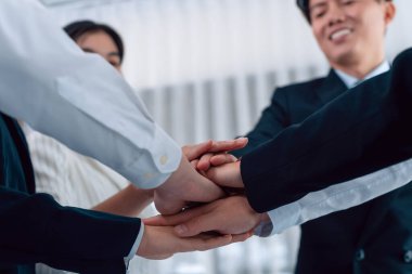 Bottom view partial hands wearing formal suit joining stack as symbol of team building, unity and harmony in office workplace. Successful business team of synergy holding hand together