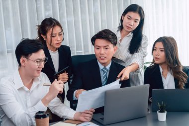 Harmony in office concept as business people analyzing dashboard paper together in workplace. Young colleagues give ideas at manager desk for discussion or strategy planning about project.