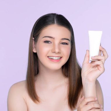 Young charming girl with natural beauty, perfect smooth skin hold lotion, cream, moisturizer tube. Beautiful girl show skincare product smiling on isolated background.