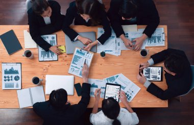 Top-view business team of financial data analysis meeting with business intelligence, report paper and dashboard on laptop for marketing strategy. Business people working together in office of harmony