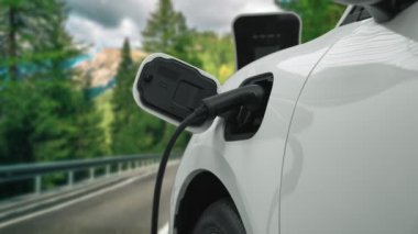 Elektrikli araç konsepti, yeşil çevre için yenilenebilir ve temiz enerjiyle çalışan EV otomobilinin varış noktasına ulaşmadan önce ormandaki şarj istasyonunun enerjisini şarj etmek için durur..