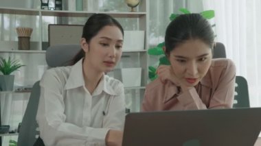 Ofis çalışma alanında birlikte çalışan iki genç hevesli iş kadını. Genç meslektaşlar tartışırken ve dizüstü bilgisayar kullanırken. Modern ofis çalışanları masada birlikte oturuyorlar..