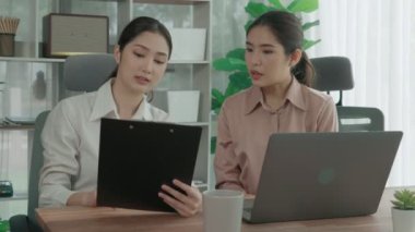 Ofis çalışma alanında birlikte çalışan iki genç hevesli iş kadını. Genç meslektaşlar tartışırken ve dizüstü bilgisayar kullanırken. Modern ofis çalışanları masada birlikte oturuyorlar..