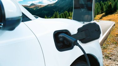 Tepe yolundaki şarj istasyonunda elektrikli arabanın çevresel farkındalığı için yenilikçi bir kavram. EV araba temiz çevre için yenilenebilir enerjiden güç alıyor.