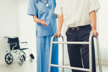 Physiotherapist assists contented senior man on folding walker. Recuperation for elderly, seniors care, nursing home.